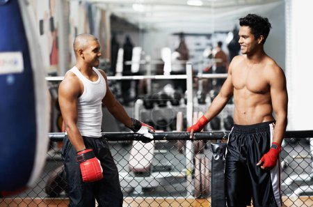 Foto de No hard feelings after sparring. two young boxers talking together in a gym - Imagen libre de derechos