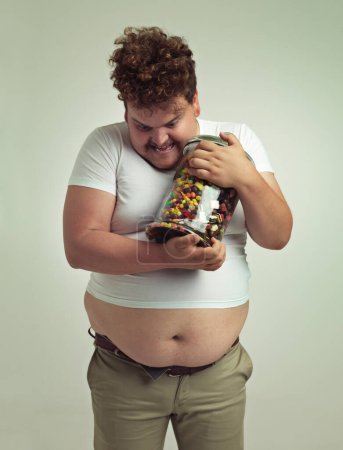 Photo for My precious. an overweight man holding on for dear life to his candy - Royalty Free Image