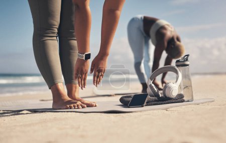 Téléchargez les photos : Sois malin. deux jeunes femmes qui s'étirent sur la plage - en image libre de droit