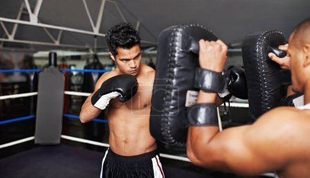 Photo for Warming up before the fight. A handsome young man warming up for the big fight with his boxing coach - Royalty Free Image