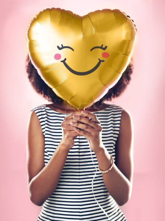 Foto de Amor, sonrisa y una mujer con un globo de corazón aislado sobre un fondo rosa en un estudio. Feliz, lindo y una chica sosteniendo un regalo o regalo para San Valentín o un cumpleaños para el cuidado y la felicidad. - Imagen libre de derechos