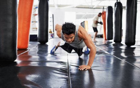 Foto de Inclínate y sé malo. Un joven boxeador enfocado haciendo flexiones en el gimnasio - Imagen libre de derechos