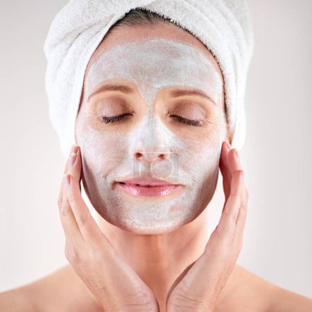 Téléchargez les photos : S'occuper de sa peau avec un soin du visage. une femme mûre avec un masque appliqué sur son visage - en image libre de droit