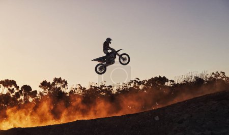 Photo for Racing against the sunset. a motocross rider going over a jump during a race - Royalty Free Image
