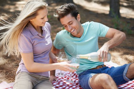Photo for Hes a real gentleman. a happy young couple enjoying a summer picnic and having a drink - Royalty Free Image