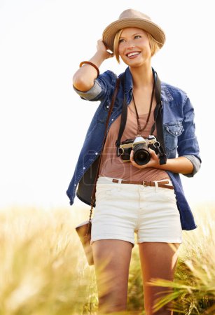 Photo for Nature is a great place for photo opportunities. An attractive young woman holding a camera while standing in a field - Royalty Free Image