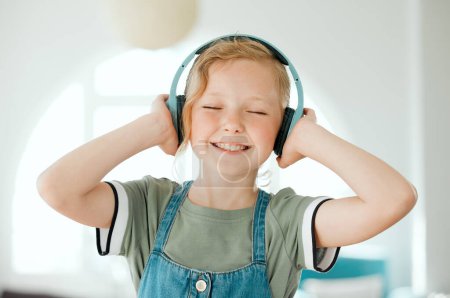 Photo for This song is so good. an adorable little girl standing alone at home and listening to music through headphones - Royalty Free Image