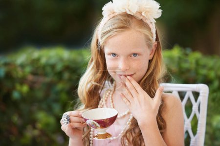 Photo for Having fun at the tea party. A cute little girl having a tea party outside - Royalty Free Image