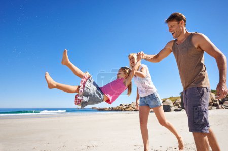 Téléchargez les photos : C'est une famille de plage. une jeune famille heureuse étant ludique tout en faisant une promenade sur la plage - en image libre de droit