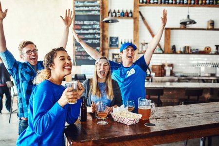 Photo for You cant beat the blue. a group of friends cheering while watching a sports game at a bar - Royalty Free Image