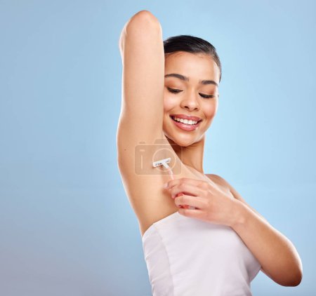 Photo for Shower and shave. Studio shot of an attractive young woman shaving her underarm against a blue background - Royalty Free Image