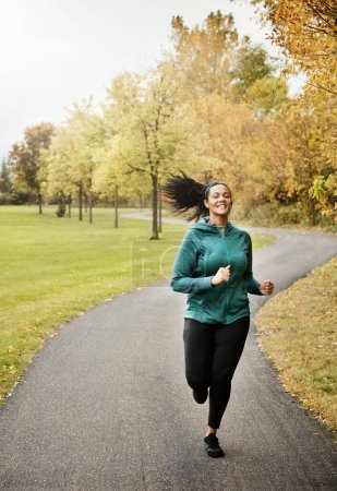 Photo for Powering through her run. Portrait of an attractive young woman going for a run in nature - Royalty Free Image