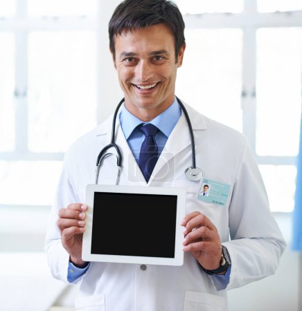 Foto de El nuevo mejor amigo de los médicos. Retrato de un guapo médico joven sosteniendo una tableta para que la pantalla esté frente a la cámara - Imagen libre de derechos