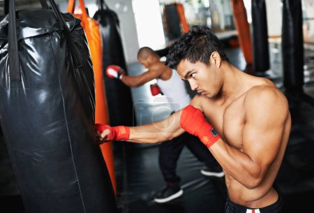 Foto de Está dedicado al deporte del boxeo. jóvenes boxeadores masculinos entrenando en bolsas pesadas - Imagen libre de derechos