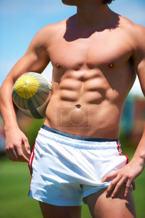 Téléchargez les photos : On est venus gagner. un jeune joueur de rugby torse nu avec la balle cachée sous son bras - en image libre de droit