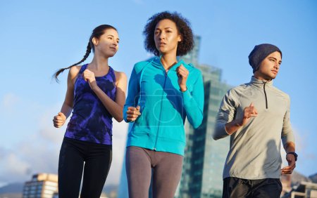 Téléchargez les photos : Elle dirige cette meute. trois jeunes joggeurs sortent courir dans la ville - en image libre de droit
