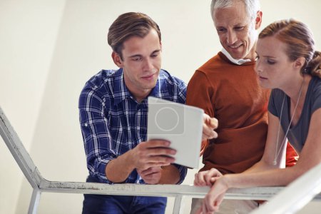 Photo for Impromptu strategy meeting. a coworkers standing in a stairwell talking over a digital tablet - Royalty Free Image