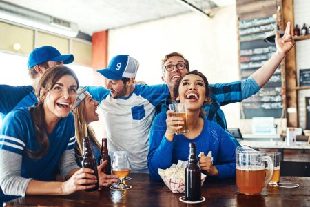 Photo for Watching the action live. a group of friends cheering while watching a sports game at a bar - Royalty Free Image