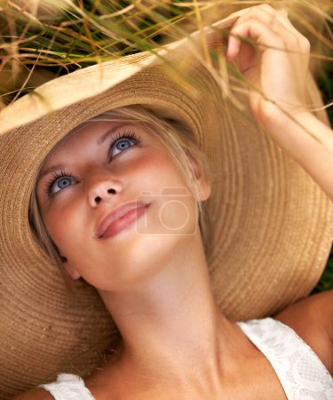 Photo for Enjoying the sweet country air. Beautiful young woman wearing a straw hat and lying in a field - Royalty Free Image