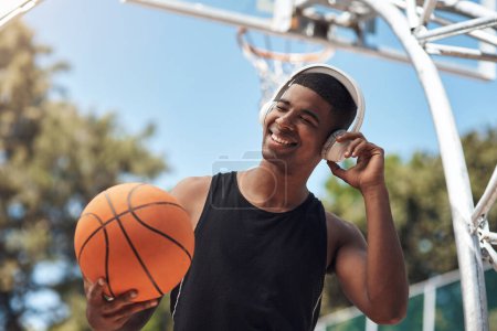 Téléchargez les photos : Cette confiture est si bonne. un jeune homme sportif écoutant de la musique tout en jouant au basket sur un terrain de sport - en image libre de droit