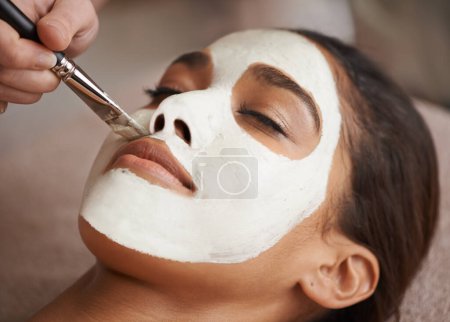 Téléchargez les photos : Détoxiquez votre peau. Un masque facial appliqué à une belle jeune femme dans un spa de beauté - en image libre de droit