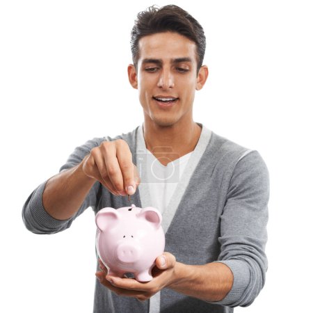 Photo for Saving for a rainy day. A handsome young man putting money into a piggybank against a white background - Royalty Free Image