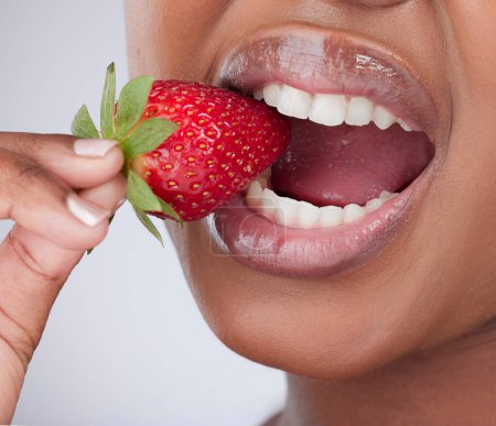 Photo for Natures candy. Cropped studio shot of an unrecognizable woman biting into a strawberry against a grey background - Royalty Free Image