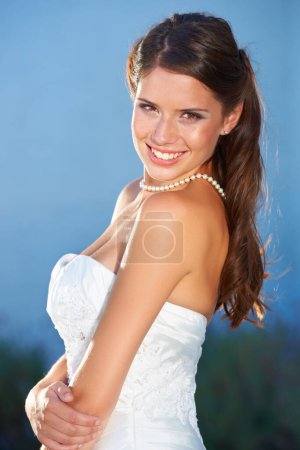 Foto de Retrato de la futura esposa encantadora. Retrato de una hermosa joven novia mirando por encima de su hombro y sonriendo a la cámara - Imagen libre de derechos
