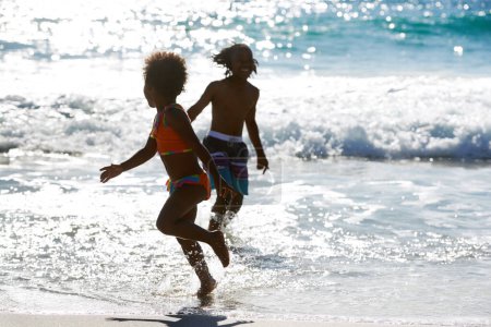 Foto de Aprovechando al máximo un día increíble. Un hermano y una hermana jugando juntos en el mar en un brillante día de verano - Imagen libre de derechos