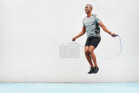 Photo for Train like a beast. Full length shot of a handsome young athlete using a skipping rope during an outdoor training session - Royalty Free Image