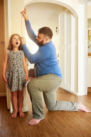 Photo for Im almost as tall as you, Dad. an adorable little girl getting measured by her father against a wall at home - Royalty Free Image