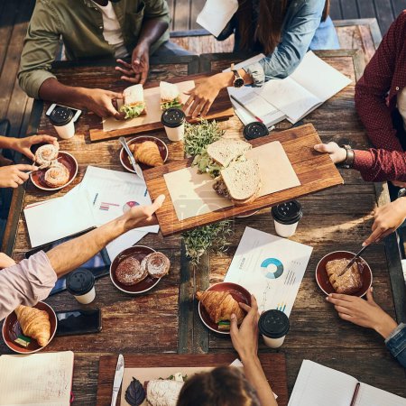 Photo for Having a productive lunch. High angle shot of a group of creative workers out on a business lunch - Royalty Free Image