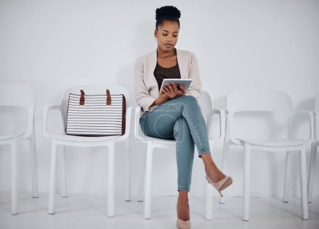 Foto de Sus aplicaciones la mantendrán ocupada. una joven empresaria que usa una tableta digital mientras está sentada en una fila sobre un fondo blanco - Imagen libre de derechos