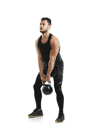 Photo for Putting in the effort to get the results he wants. Studio shot of a fit young man working out with a kettle bell against a white background - Royalty Free Image
