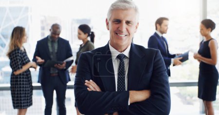 Photo for Nothing can bring down a happy man. a handsome businessman smiling at the camera while colleagues are blurred in the background - Royalty Free Image
