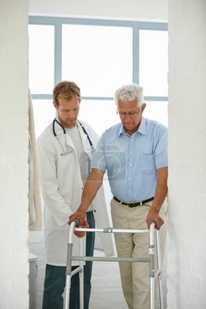 Foto de Un paso a la vez... un médico masculino asistiendo a su paciente mayor que usa un andador como apoyo. - Imagen libre de derechos