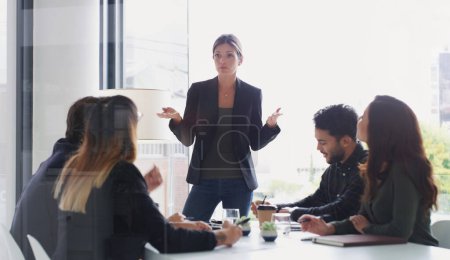 Photo for Updating her team on the companys progress. a young businesswoman giving a presentation to her colleagues in an office - Royalty Free Image