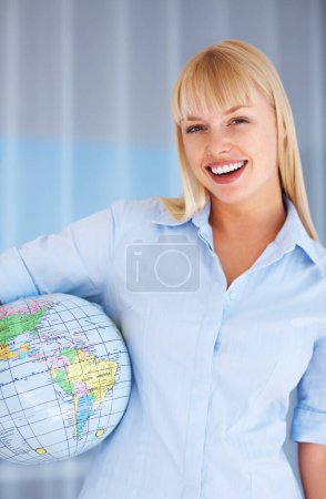 Téléchargez les photos : Femme d'affaires internationale. Femme d'affaires souriante tenant globe à ses côtés - en image libre de droit