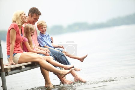 Téléchargez les photos : Famille, vacances et eau avec maquette et pied au lac pendant l'été pour voyager avec amour. Enfant, parent et aventure à la rivière sur le pont avec liberté de se détendre avec espace et temps pour le mode de vie - en image libre de droit