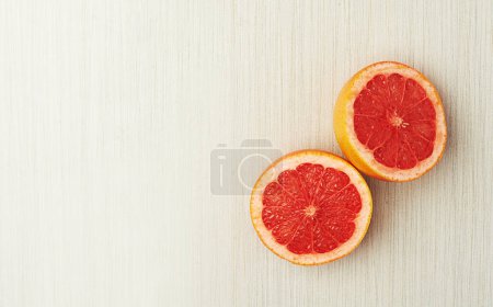 Photo for Juicy nutrients. Top view of a halved grapefruit lying on a light wooden surface - Royalty Free Image