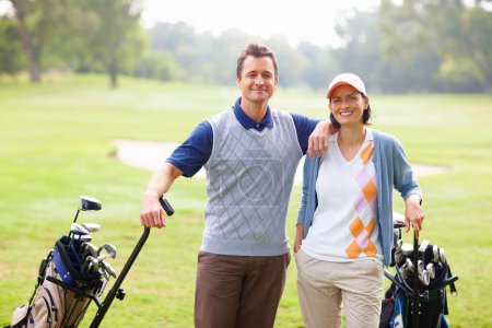 Téléchargez les photos : Un couple de golf. Portrait de couple debout sur l'herbe avec kit de golf et sourire - en image libre de droit