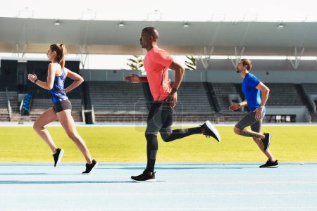 Photo for The race is on. Full length shot of three young athletes running along the track together - Royalty Free Image