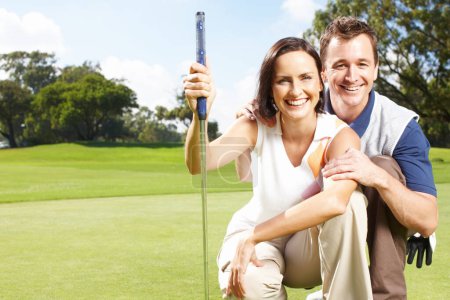 Photo for They enjoy golfing together as a hobby. Young couple smiling and crouched together on the golf course - Royalty Free Image