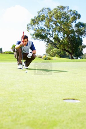 Foto de Hombre golfista alineando el putt. Longitud completa del golfista masculino agachado en el putting green alineando el putt - Imagen libre de derechos