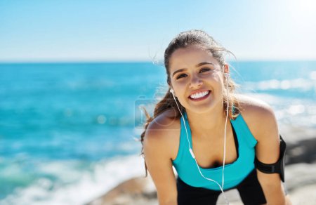 Photo for Music makes me beat my target. a sporty young woman listening to music while out for her workout - Royalty Free Image
