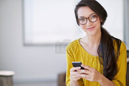 Foto de La satisfacción del cliente es mi principal objetivo. una joven atractiva usando un teléfono celular en una oficina - Imagen libre de derechos