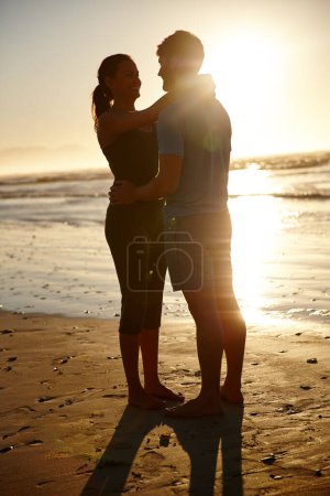Photo for Moments to share and remember. a hugging couple silhouetted against a sunrise over the sea - Royalty Free Image