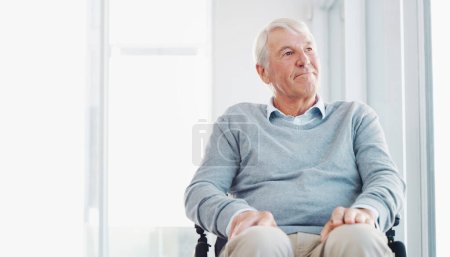 Téléchargez les photos : Le mouvement n'est pas aussi facile de nos jours. un homme âgé dans un fauteuil roulant regardant pensivement par une fenêtre - en image libre de droit
