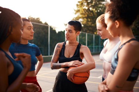 Téléchargez les photos : L'écoute fait partie du jeu. un groupe diversifié d'amis se préparant à jouer à un jeu de basket-ball ensemble pendant la journée - en image libre de droit