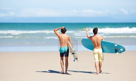 Téléchargez les photos : Excité pour un peu de surf. Deux amis à la plage se préparent à aller surfer sur l'eau - en image libre de droit